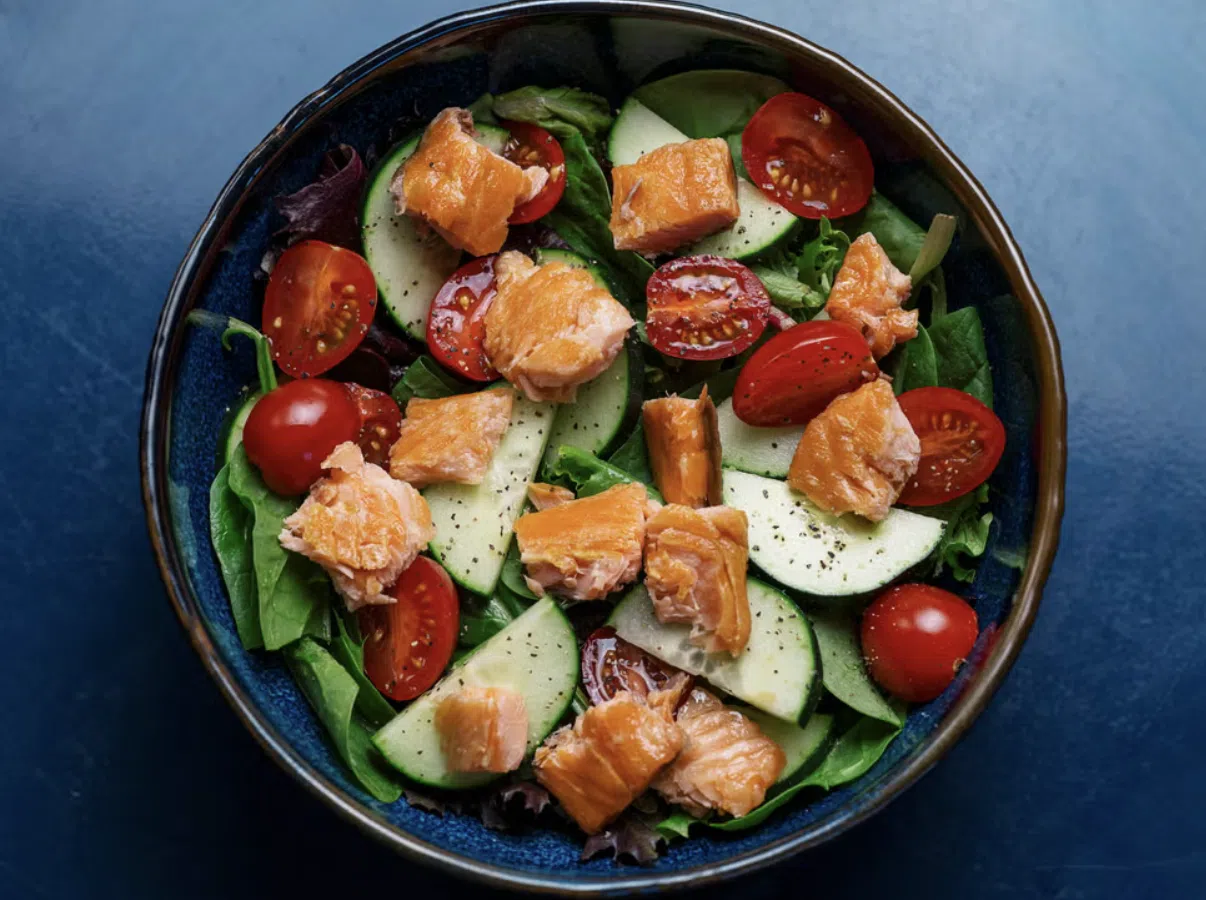 Kom met salade, zalm, tomaatjes en komkommer.